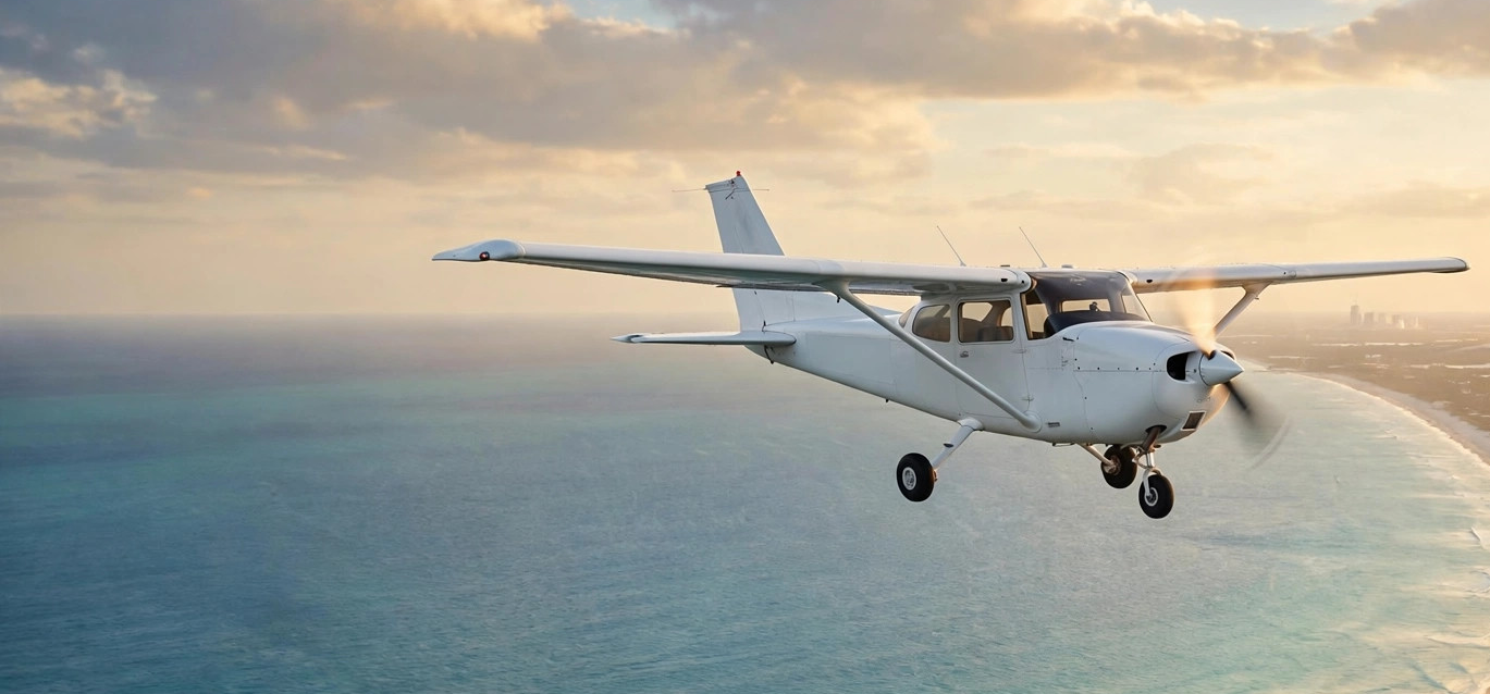 Single-engine aircraft flying over the Florida coastline at golden hour
